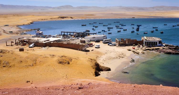 Kleine Fischersiedlung und Anlegestelle auf einer sandigen Halbinsel an einer ruhigen blauen Bucht.
