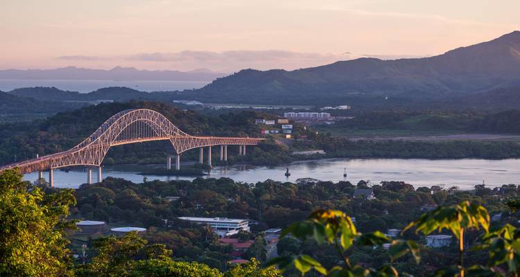 Vue à l'heure dorée du Pont des Amériques enjambant le Canal de Panama avec des collines à l'arrière-plan.