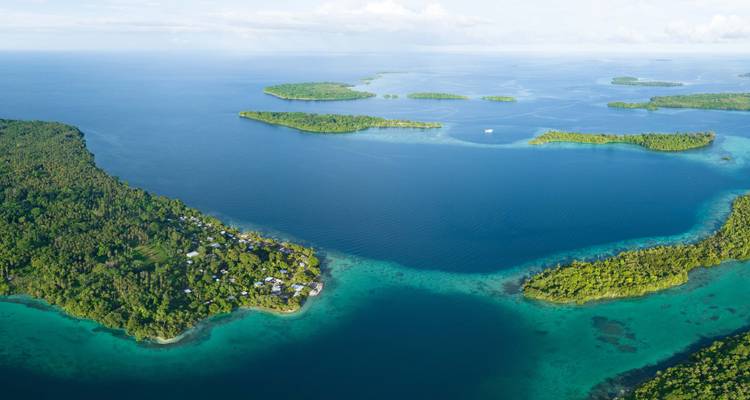 Luchtfoto van smaragdgroene jungle-eilanden en turquoise lagunes verspreid over een uitgestrekte tropische zee.