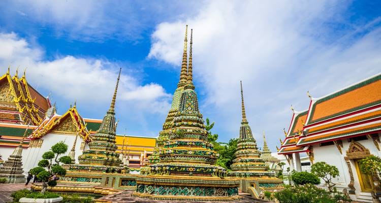 Bunte Chedis und verzierte Dächer des Wat Pho Tempelkomplexes unter blauem Himmel.