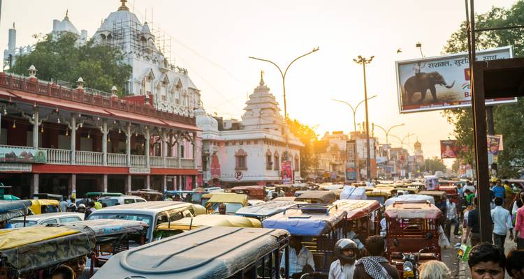 Crowded city street filled with auto-rickshaws near a Hindu temple at sunset