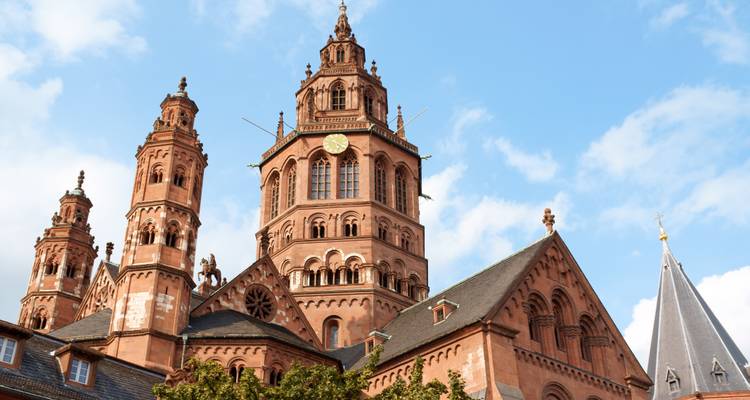 Nahaufnahme der kunstvollen Türme und Spitzen des Mainzer Doms vor blauem Himmel.