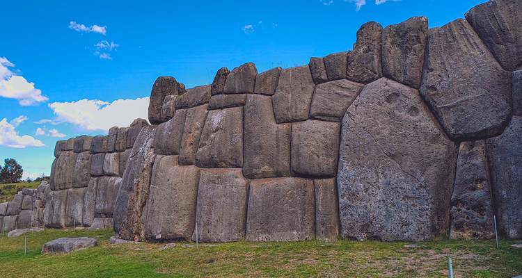 Massive ineinander greifende Steinwälle von Sacsayhuamán erheben sich unter einem strahlend blauen Andenhimmel.
