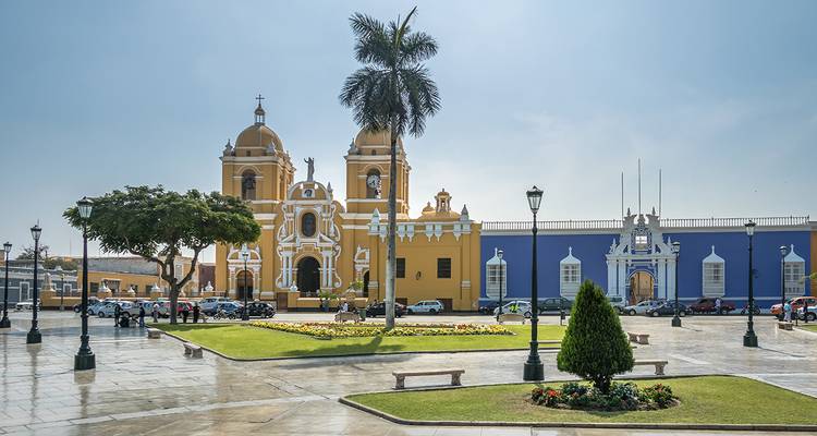 Farbenfrohe Kolonialkathedrale und Platz in Trujillo mit Einheimischen und Autos nach Regen.