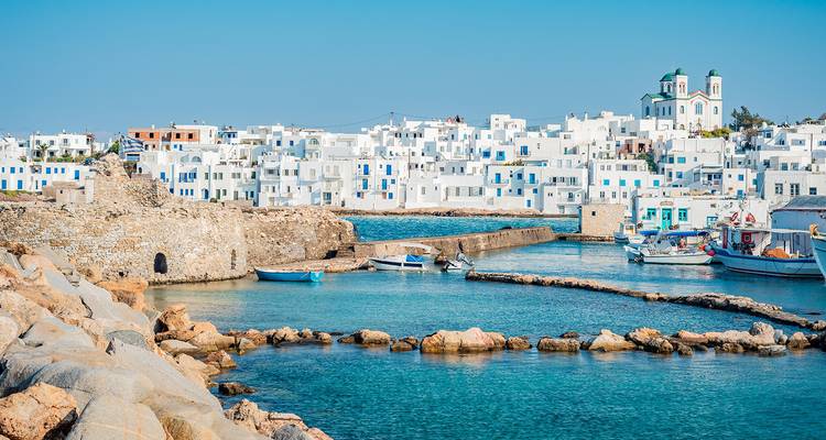 Le village cycladique d'un blanc éclatant de Naoussa entoure un port turquoise sous un ciel dégagé.