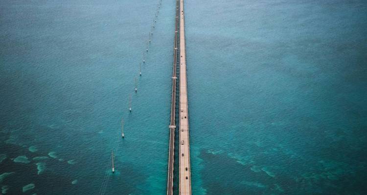 Recht luchtperspectief van een lange brug die zich uitstrekt over diepblauwe oceaanwateren.
