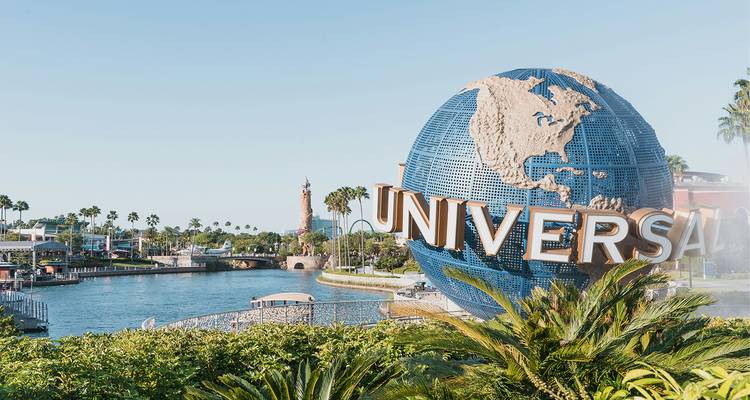Globo emblemático de Universal Studios junto a un lago y un paseo bordeado de palmeras en Orlando.