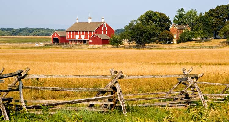 Escena rural de Gettysburg con un granero rojo clásico y cercas de rieles divididos a través de campos dorados.