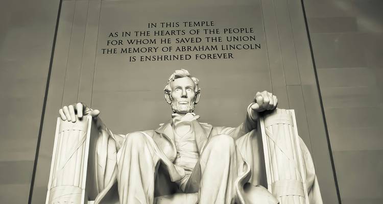 Marmeren standbeeld van Abraham Lincoln zittend in het Lincoln Memorial met gegraveerde inscriptie erboven.