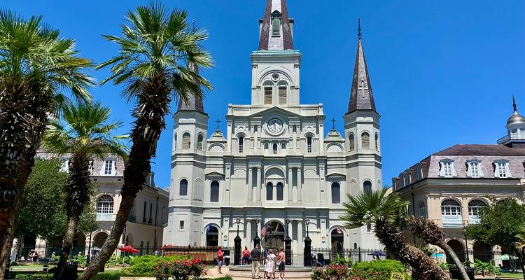 La Catedral de San Luis se alza sobre la Plaza Jackson bordeada de palmeras bajo un cielo azul intenso en Nueva Orleans.