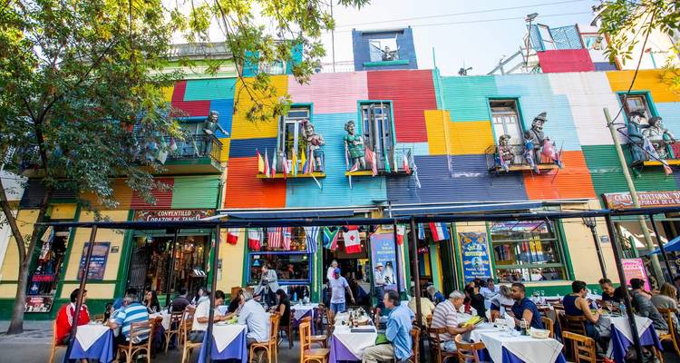 Bruisende terrassencafés staan langs een levendig geschilderde gevelbouw in een levendige stadsstraat.