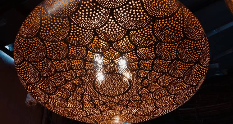 Artistieke close-up van een geperforeerde metalen lantaarn die ingewikkelde warme lichtpatronen werpt.