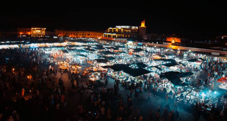 Nachtbeeld van het bruisende Jemaa el-Fnaa-plein dat gloeit van de honderden voedselstalletjes en bezoekers.