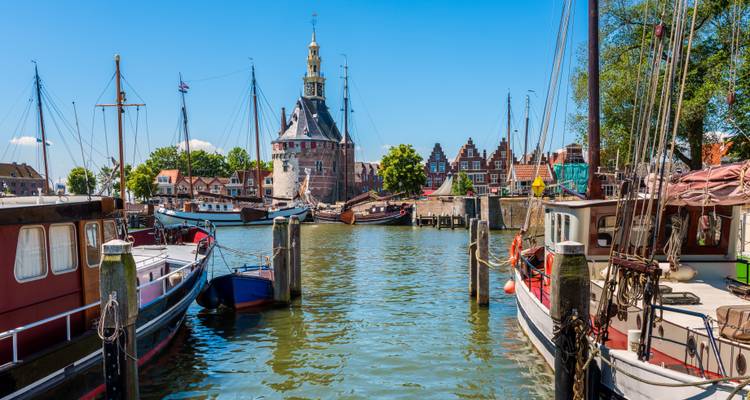 Sonnige Hafenszene in Hoorn mit historischem Turm, vertäuten Segelbooten und Häusern mit Giebeldächern aus Backstein.