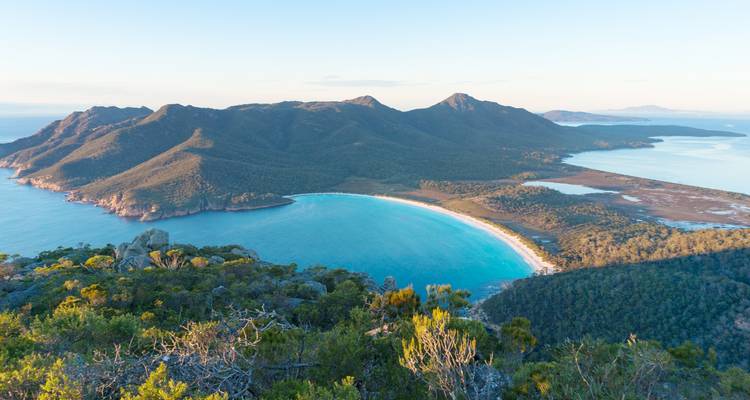 Luftaufnahme der perfekten türkisfarbenen Kurve der Wineglass Bay, umgeben von bewaldeten Bergen im Freycinet-Nationalpark.