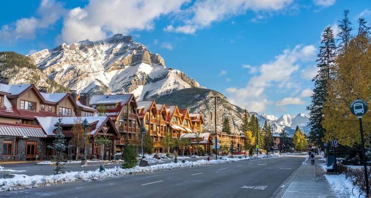 Calle de pueblo de montaña pintoresco con cabañas de madera y picos nevados idéntica a la escena anterior de Banff.