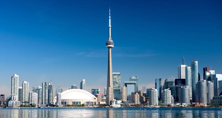 Vue dégagée de l'horizon de Toronto avec la Tour CN se reflétant dans le lac Ontario sous un ciel sans nuages.