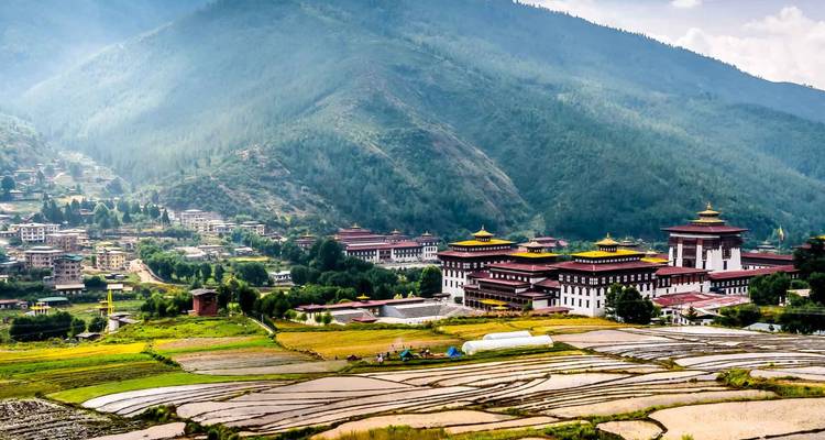 Panoramablick auf das Tal von Thimphu mit traditionellen Dzong-Gebäuden und terrassierten Feldern.