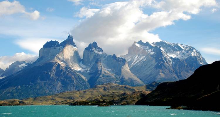 Dramatische Torres del Paine Gipfel, die sich über türkisfarbenen See unter wirbelnden Wolken erheben