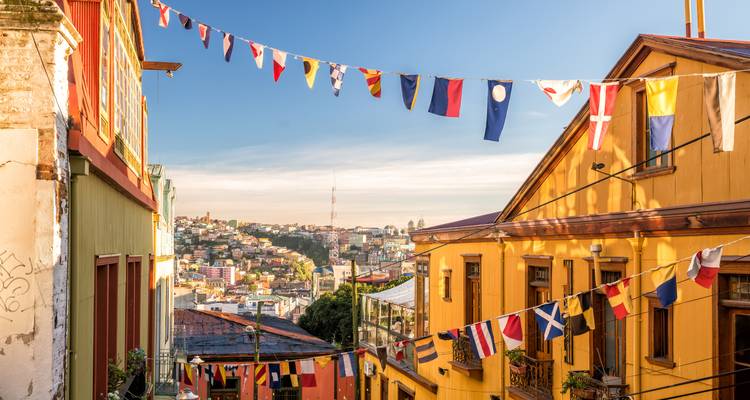 Bunte Hanghäuser und maritime Signalflaggen säumen schmale Straße in Valparaiso bei goldenem Licht