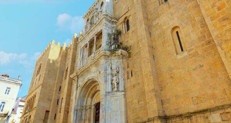 Fachada de piedra de una catedral antigua con portal de mármol ornamentado contra el cielo azul.