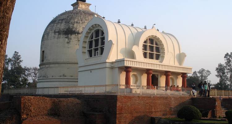 Temple de Mahaparinirvana au dôme blanc situé au sommet de socles de briques anciennes avec des visiteurs au crépuscule.