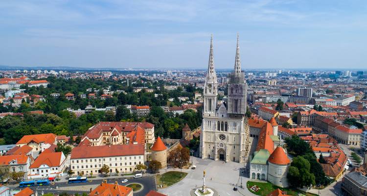 Dronebeeld van de Kathedraal van Zagreb die boven het stadslandschap met rode daken uittorent.