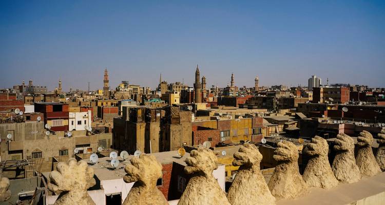 Dakpanorama van historisch Caïro met minaretten die uitsteken boven dichtbebouwde gebouwen.