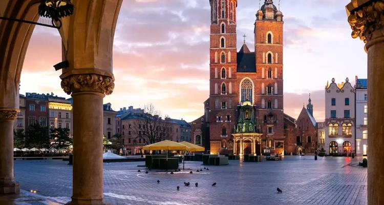 Die Marienbasilika überblickt den leeren Hauptplatz im Morgengrauen in Krakau mit warmem Himmel