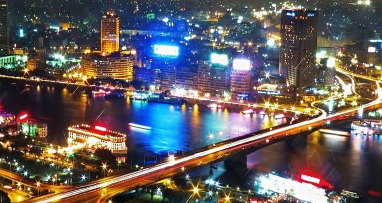 Lebendige nächtliche Skyline von Kairo mit beleuchteten Brücken, die den Nil überqueren.