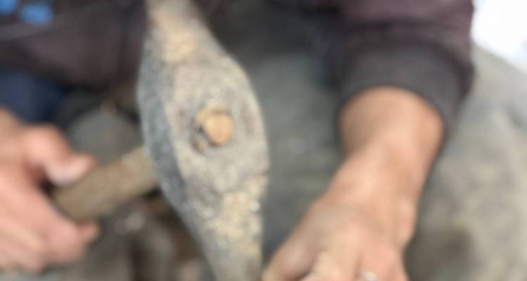 Gros plan très flou d'une personne utilisant un marteau sur un petit objet.