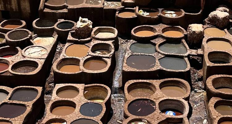 Vue aérienne de cuves de tannage colorées remplies de teintures et d'eau dans une tannerie traditionnelle.