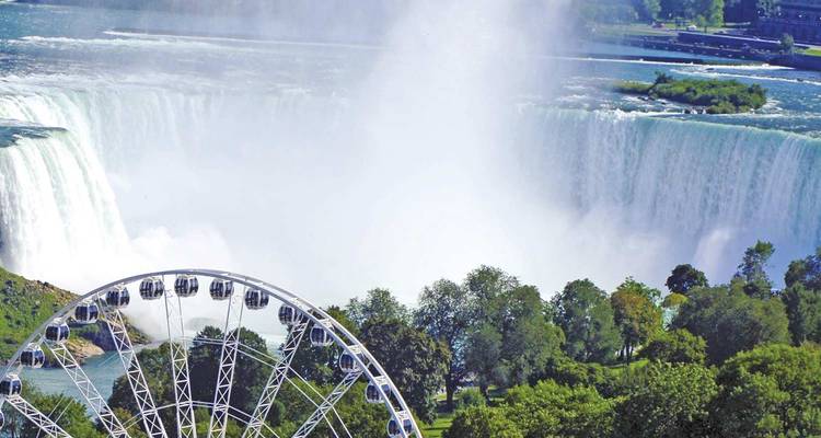 La niebla se eleva de las imponentes Cataratas Herradura en las Cataratas del Niágara con una rueda de la fortuna y exuberantes zonas verdes en primer plano.