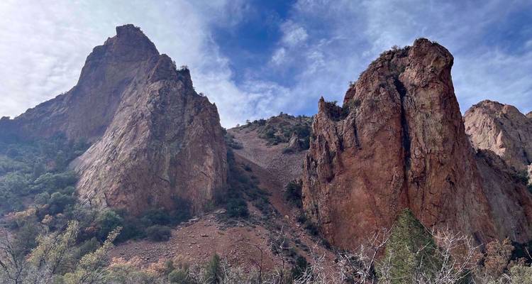 Falaises rouges abruptes et pentes rocheuses sous des nuages striés dans l'arrière-pays de Big Bend