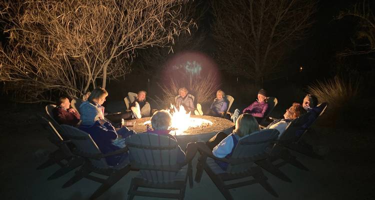 Groupe de voyageurs assis autour d'un feu de camp lumineux sous les arbres du désert nocturne