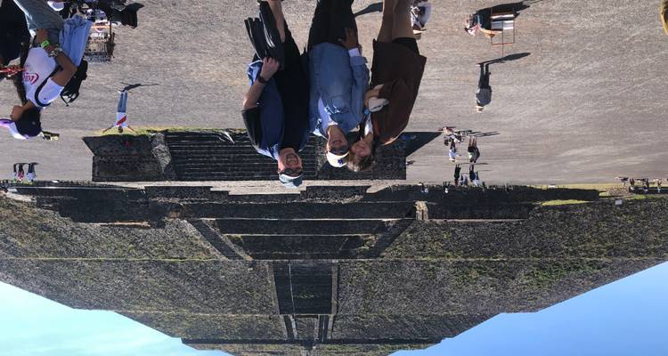 Drei Reisende lächeln vor der enormen Sonnenpyramide.