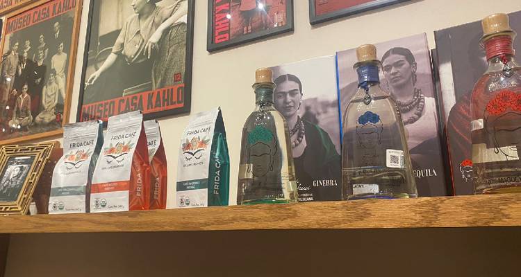 Regalauslage von Frida Kahlo Marken-Kaffee und Tequila-Flaschen mit Postern dahinter.