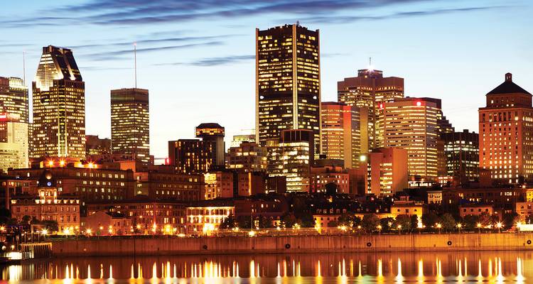De verlichte skyline van Montreal weerspiegelt zich in de rustige Sint-Laurentiusrivier tijdens het blauwe uur.
