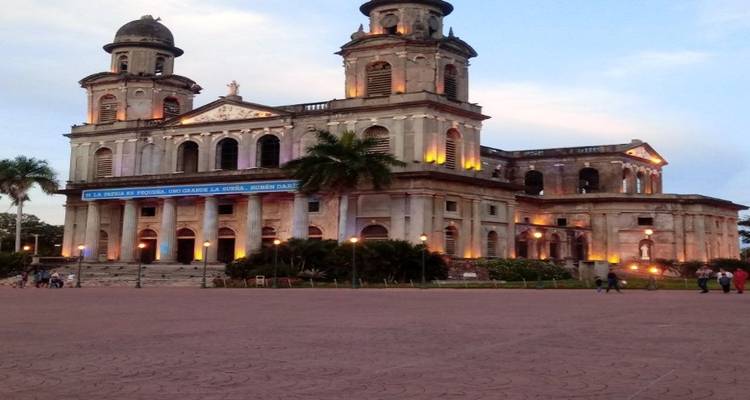 Historische kathedraal van Managua verlicht met warme lichten bij schemering op leeg plein.