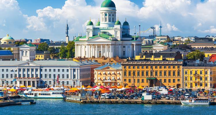 La Catedral de Helsinki con vista a los puestos de mercado bulliciosos a lo largo del malecón en un día soleado.