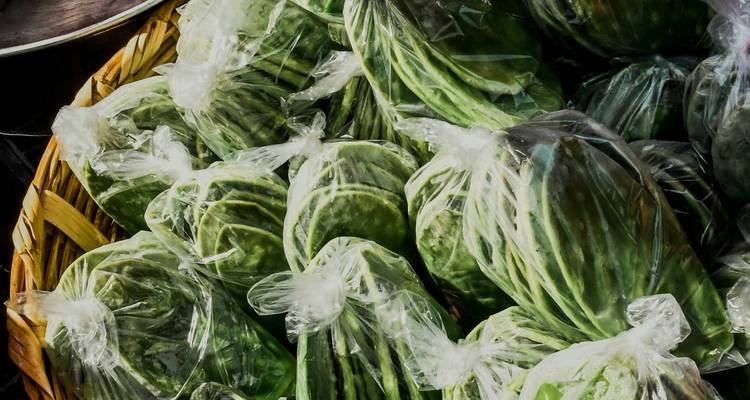 Nahaufnahme von frischen grünen Nopales, die eng in Plastiktüten verpackt auf einem Straßenmarkt liegen.