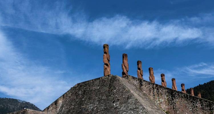 Skulpturale Steinpfeiler, die sich gegen einen strahlend blauen Himmel auf einer gestuften Plattform abzeichnen.
