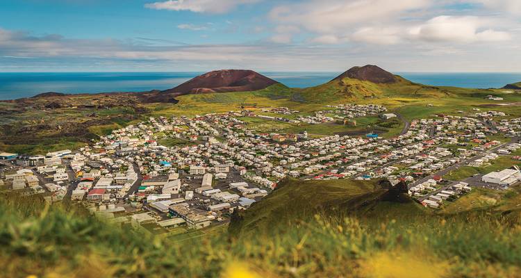 Vue panoramique sur la ville de Heimaey située entre deux cônes volcaniques et l'océan
