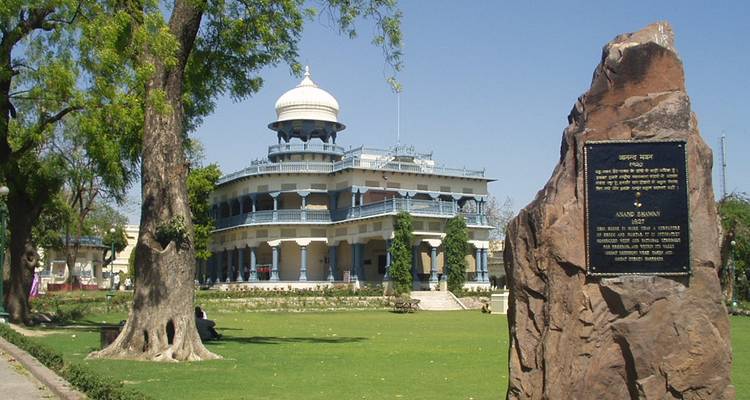 Manoir colonial Anand Bhavan entouré de pelouses soignées et d'arbres par une journée ensoleillée.