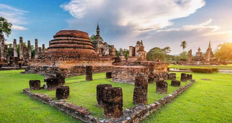 Ancient brick stupa ruins surrounded by green lawns under a glowing afternoon sky