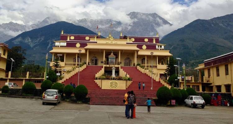 Verziertes gelbes Klostergebäude mit roten Stufen vor imposanter Himalaya-Kulisse
