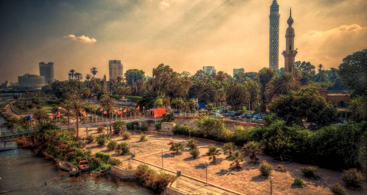Uferpark entlang des Nils in Kairo mit dem Kairoer Turm und Moscheeminarett unter warmem spätnachmittäglichem Licht.