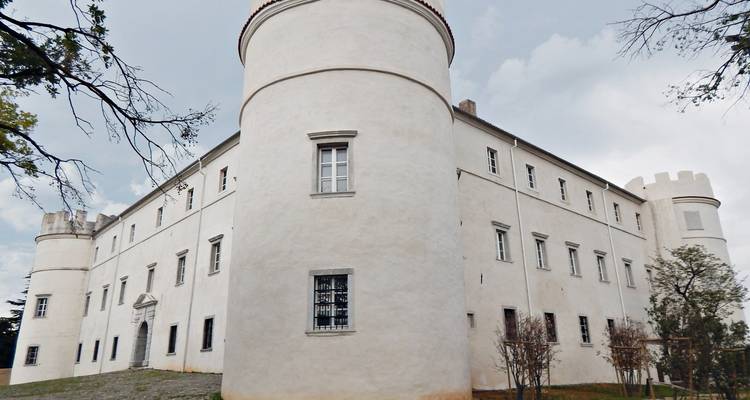 Wit cilindrisch torenslot dat hoog oprijst tegen een bewolkte hemel.