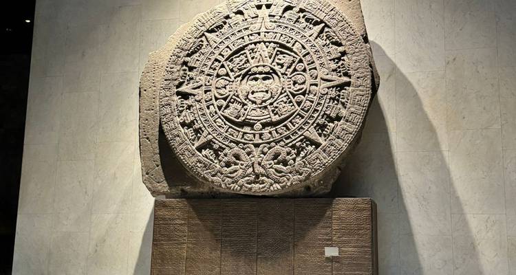 Aztekischer Sonnenstein auf einem Sockel in einer schwach beleuchteten Museumsgalerie ausgestellt