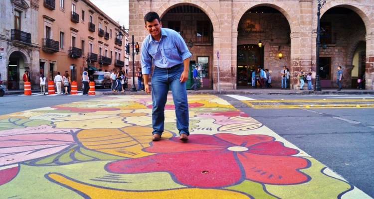 Man enjoying a colorful floral street mural painted on the pavement in Morelia's historic center.